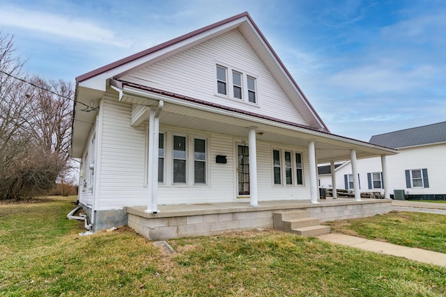 view of front of home with central AC unit, covered porch, and a front lawn