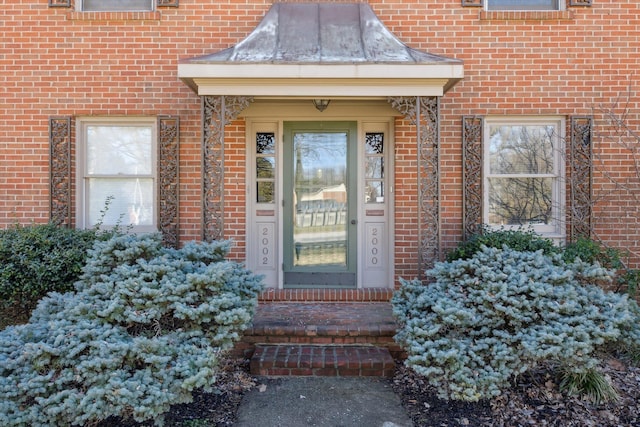 property entrance featuring a standing seam roof, metal roof, and brick siding