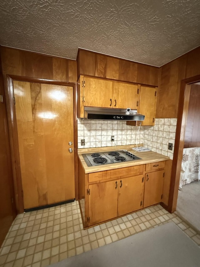 kitchen featuring electric stovetop, decorative backsplash, and wood walls