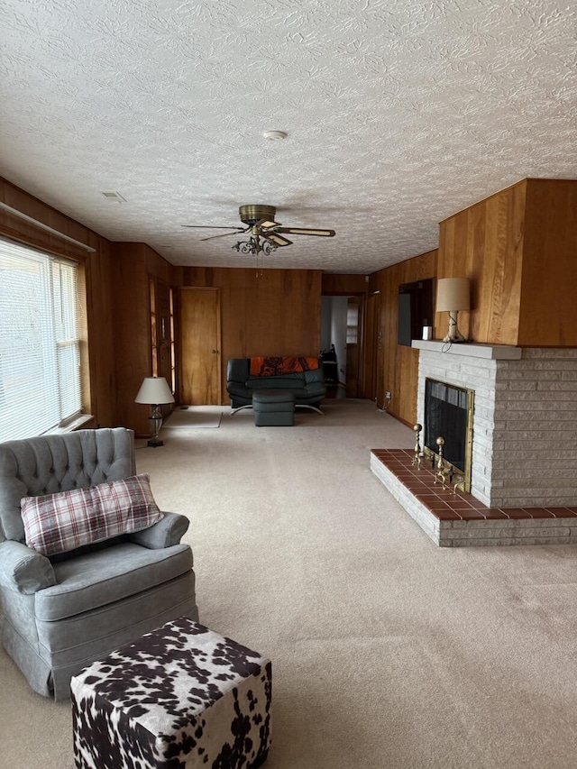 unfurnished living room featuring ceiling fan, a fireplace, a textured ceiling, light colored carpet, and wood walls