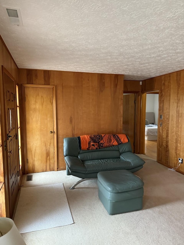 carpeted living room featuring wooden walls and a textured ceiling