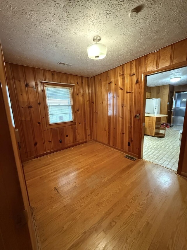 spare room featuring light hardwood / wood-style floors and a textured ceiling