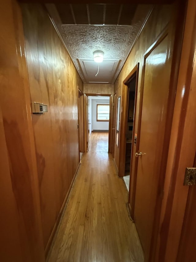 hallway with light hardwood / wood-style floors and wood walls