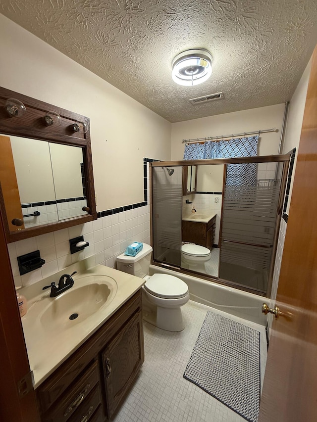 full bathroom with tile patterned floors, toilet, tile walls, vanity, and enclosed tub / shower combo