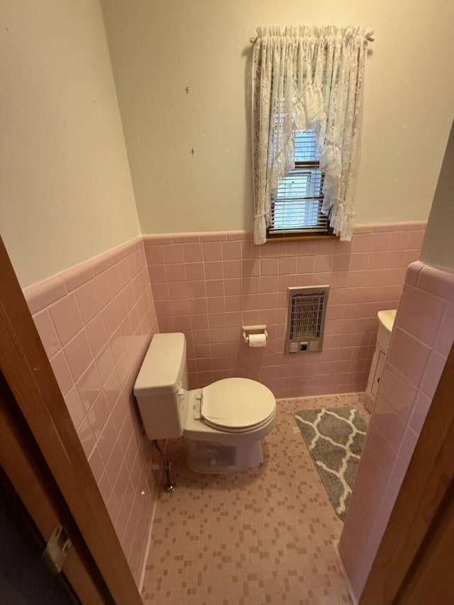 bathroom with heating unit, tile walls, and toilet