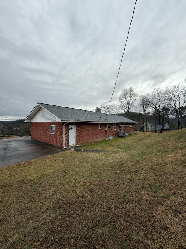 exterior space featuring cooling unit and a front lawn