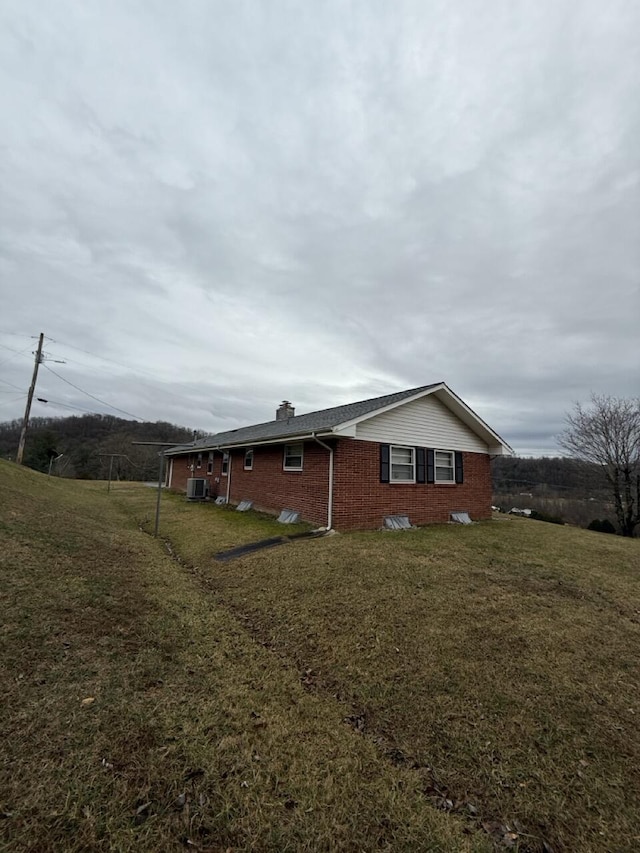 view of side of home featuring cooling unit and a yard