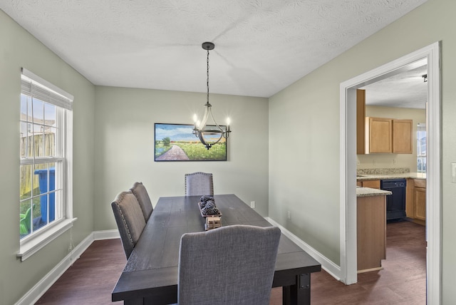 dining area featuring dark hardwood / wood-style flooring, a textured ceiling, and an inviting chandelier