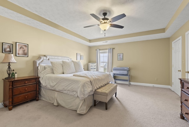 bedroom featuring ceiling fan, light colored carpet, a raised ceiling, and a textured ceiling