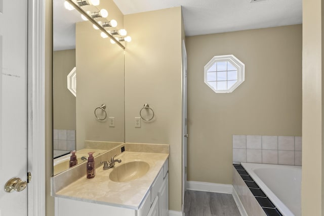 bathroom with vanity, tiled tub, and wood-type flooring