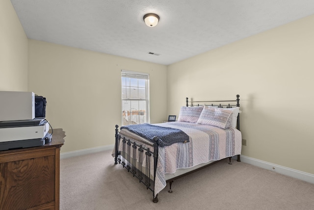 bedroom featuring light carpet and a textured ceiling