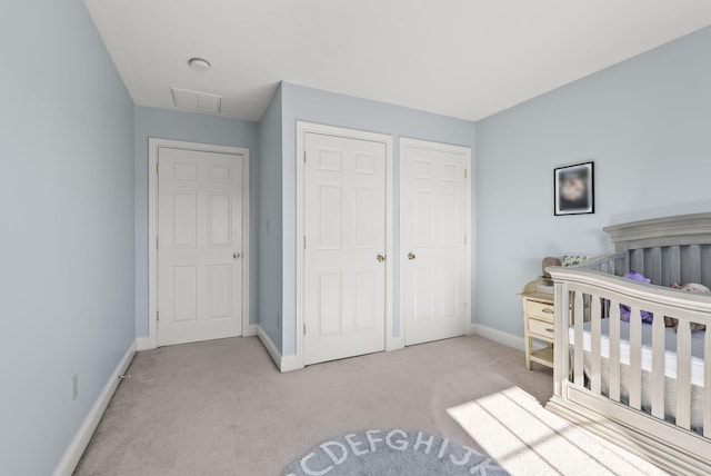 bedroom with a closet, light carpet, and a crib