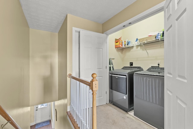 laundry area featuring washing machine and dryer, light carpet, and a textured ceiling