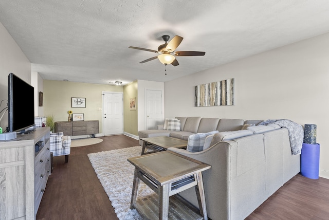 living room featuring ceiling fan, a textured ceiling, and dark hardwood / wood-style flooring