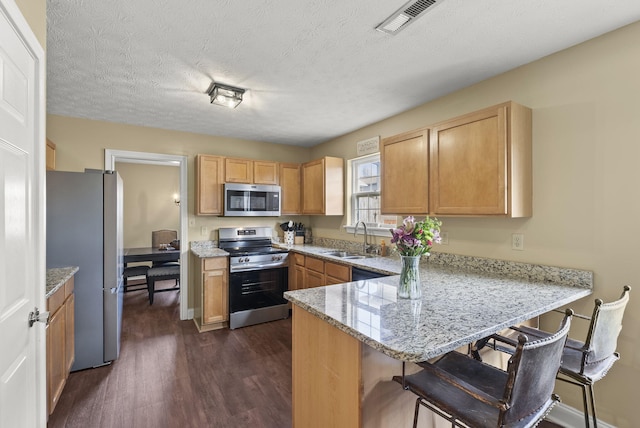 kitchen with sink, a breakfast bar, kitchen peninsula, and appliances with stainless steel finishes