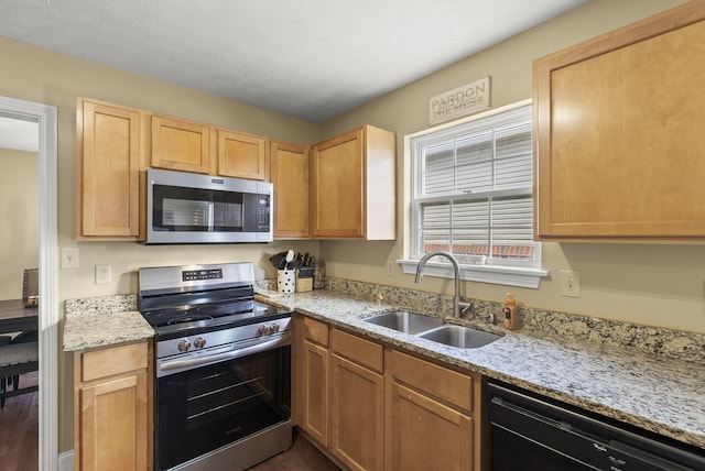 kitchen featuring stainless steel appliances, light stone countertops, sink, and light brown cabinets