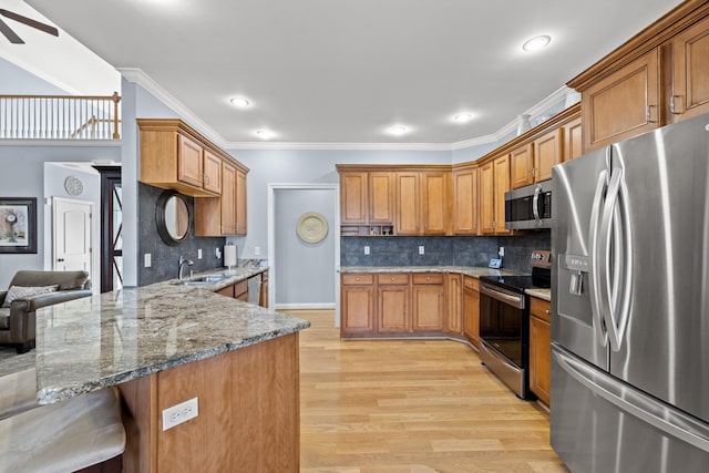 kitchen with a sink, appliances with stainless steel finishes, a kitchen bar, and brown cabinets