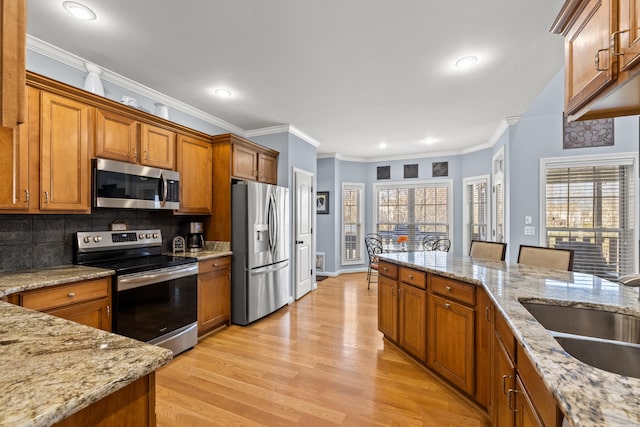 kitchen with appliances with stainless steel finishes, a sink, and brown cabinets