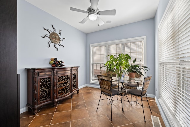 dining space with ceiling fan, dark tile patterned flooring, visible vents, and baseboards