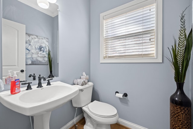 half bathroom featuring toilet, baseboards, and a sink