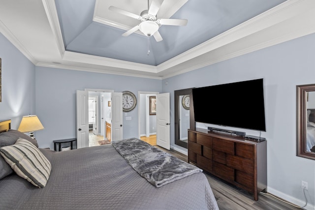 bedroom with light wood-style floors, baseboards, a tray ceiling, and crown molding