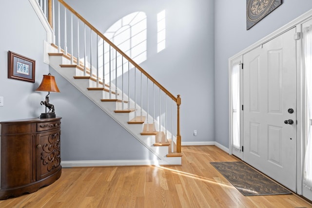 entryway featuring plenty of natural light, a high ceiling, baseboards, and light wood-style flooring