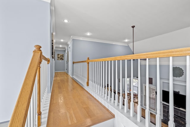 corridor with an upstairs landing, light wood-style flooring, crown molding, and recessed lighting