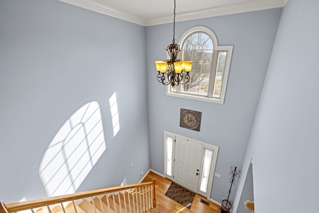 entryway featuring wood finished floors, visible vents, baseboards, an inviting chandelier, and crown molding