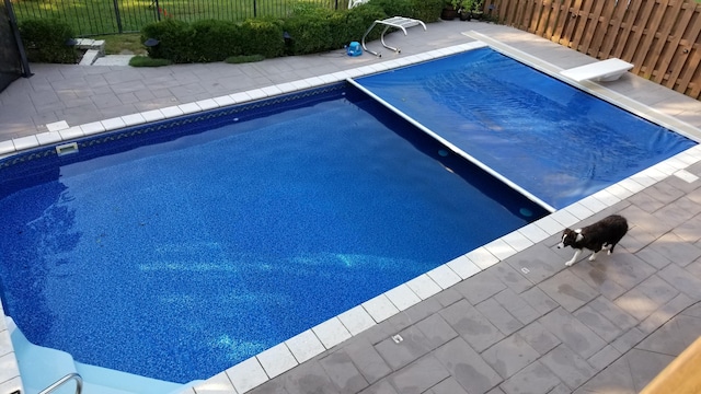 view of pool featuring fence, a diving board, a fenced in pool, and a patio