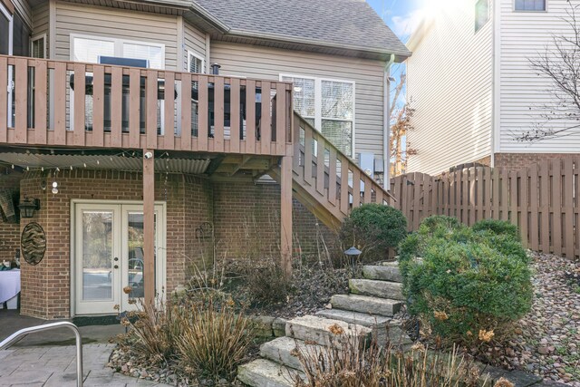 back of house with stairway, roof with shingles, fence, french doors, and brick siding