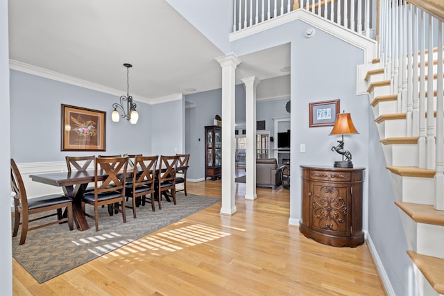 dining area with baseboards, ornamental molding, stairway, light wood finished floors, and ornate columns