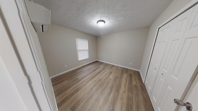 unfurnished bedroom featuring light hardwood / wood-style floors, a textured ceiling, and a closet