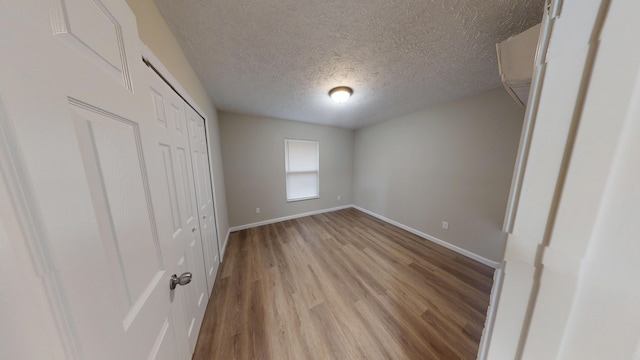 unfurnished bedroom with a closet, a textured ceiling, and light wood-type flooring