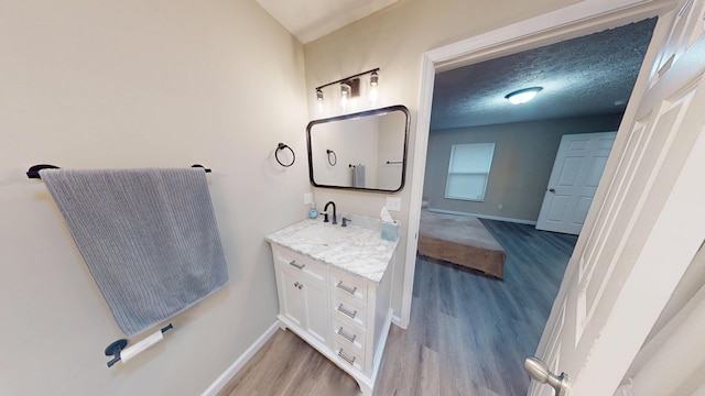 bathroom with wood-type flooring, vanity, and a textured ceiling