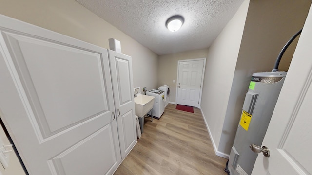 laundry room with washer hookup, water heater, a textured ceiling, and light wood-type flooring