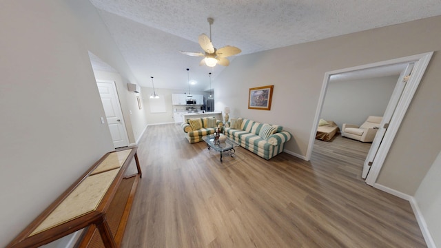 living room with ceiling fan, light hardwood / wood-style floors, vaulted ceiling, and a textured ceiling