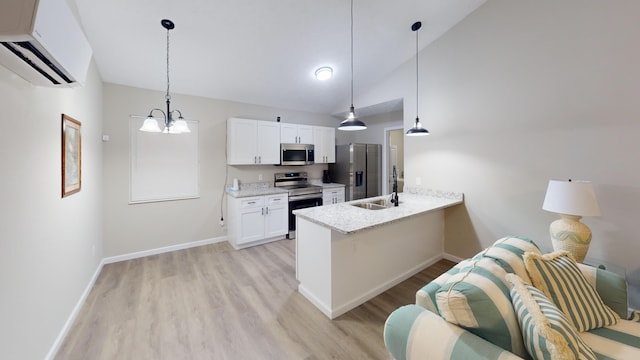 kitchen featuring an AC wall unit, pendant lighting, white cabinetry, light stone counters, and stainless steel appliances