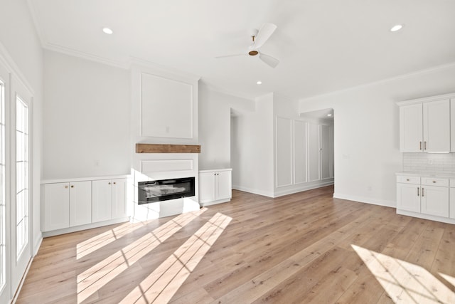 unfurnished living room with crown molding, ceiling fan, and light hardwood / wood-style flooring