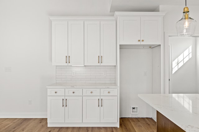 kitchen featuring hanging light fixtures, white cabinets, and light stone counters