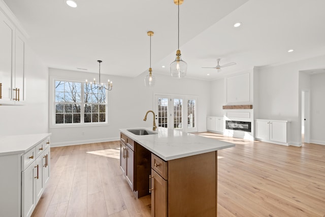 kitchen featuring white cabinetry, sink, and an island with sink