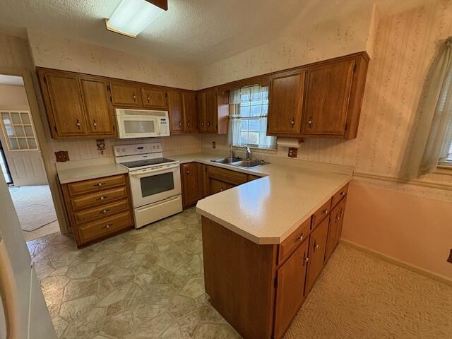 kitchen featuring white appliances, kitchen peninsula, sink, and a textured ceiling