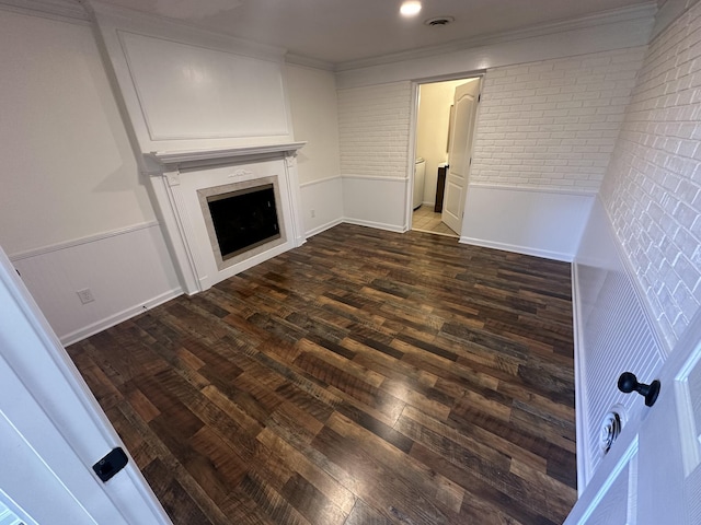 unfurnished living room featuring ornamental molding, brick wall, and dark hardwood / wood-style flooring