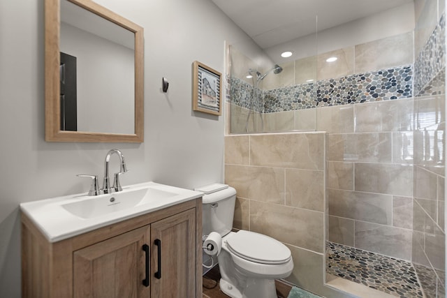 bathroom featuring vanity, toilet, and a tile shower