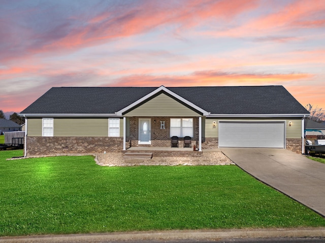 ranch-style house featuring a garage, covered porch, and a lawn