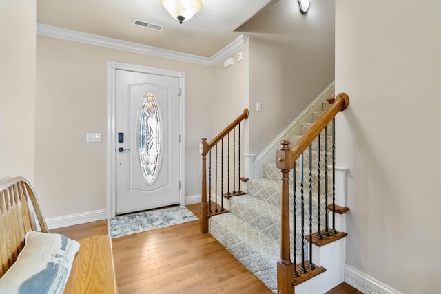 foyer entrance with ornamental molding and light wood-type flooring