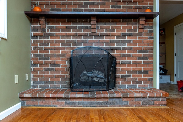 details featuring a fireplace, baseboards, and wood finished floors