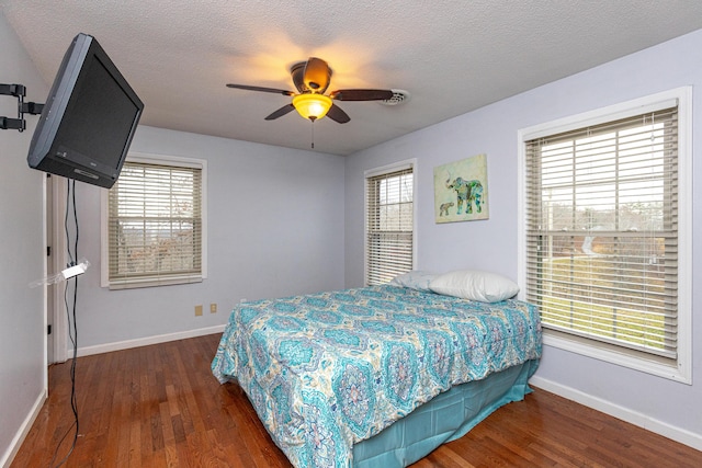 bedroom featuring ceiling fan, a textured ceiling, baseboards, and wood finished floors