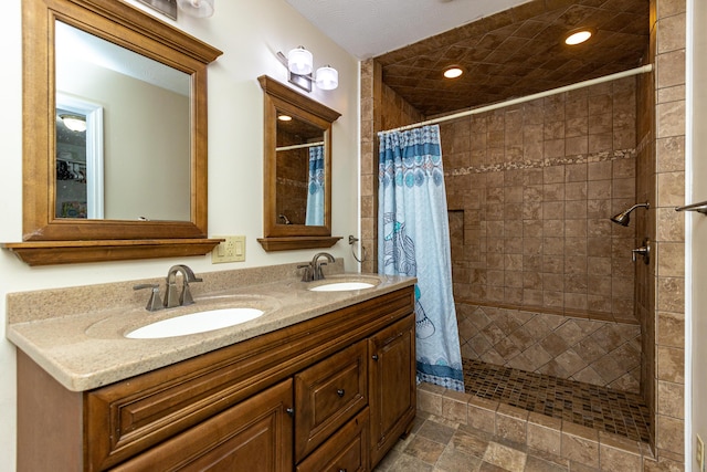 full bathroom featuring double vanity, a tile shower, a sink, and recessed lighting