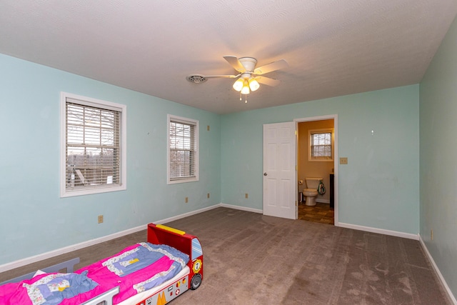 carpeted bedroom with ceiling fan, ensuite bath, visible vents, and baseboards