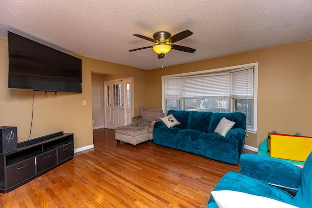 living room with baseboards, ceiling fan, a textured ceiling, and light wood finished floors